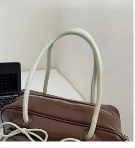 Detail of soft handle and smooth glossy leather on vintage brown bow shoulder bag