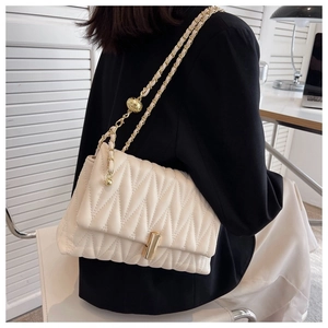 Quilted wave pattern small square bag with gold chain and ball charm on model