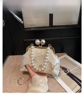 Détail du sac vintage crème avec broderie dorée et grande poignée en perles