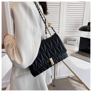 Detail of black quilted leather bag with gold chain strap and metal ball adjuster