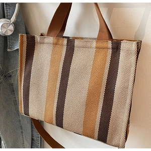 Close-up of striped canvas tote bag with shoulder straps and casual denim styling