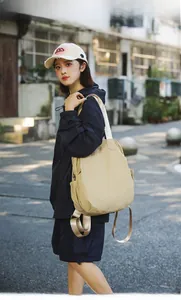 Outdoor shot of a beige waterproof nylon backpack featuring wide adjustable straps