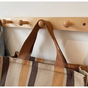 Detailed texture of brown striped canvas tote bag hanging on wooden coat rack