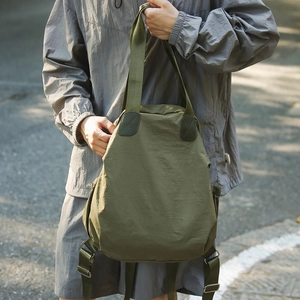 Outdoor shot of army green waterproof nylon backpack with wide straps and top handle