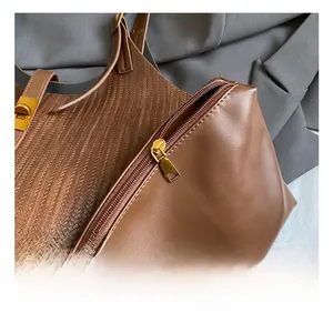 Close-up of golden zipper and swivel lock on brown patchwork leather tote bag