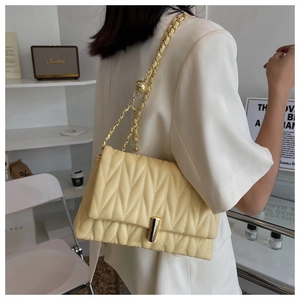 Detail of creamy yellow quilted crossbody bag featuring golden chain and twist lock