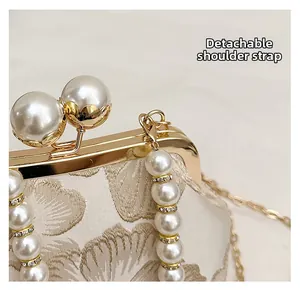 Close-up of beige brocade handbag with pearl clasp and detachable beaded strap