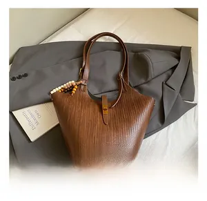 Close-up of brown woven tote bag featuring V-pattern texture and stylish wooden bead charm