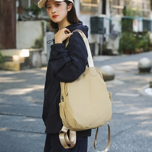 Outdoor shot of a cream waterproof nylon backpack with side pockets and adjustable straps