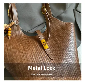Detail of woven brown leather tote featuring a gold hardware lock and beaded strap charm