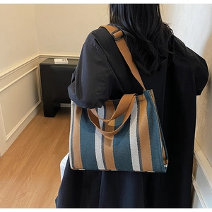 Back view of model carrying a striped large capacity canvas tote bag in earthy tones