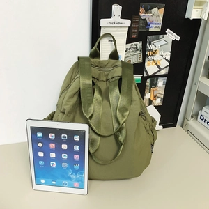 Army green nylon backpack detail showing side elastic pocket and top handle with iPad reference