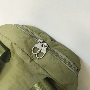 Detail of olive green nylon backpack featuring durable dual metal zippers with CLBD logo