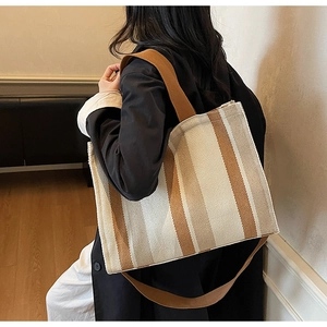 Detailed view of striped canvas tote bag with wide brown shoulder straps and roomy design