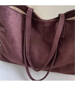 Detail of the smooth shoulder strap and soft suede texture on a deep burgundy tote bag