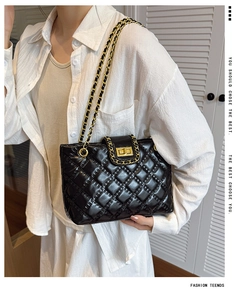 Detail of black quilted tote bag featuring golden twist lock and metal chain strap