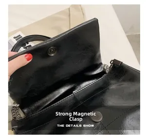 Detail view of the strong magnetic closure and vintage pleated leather on a black bag
