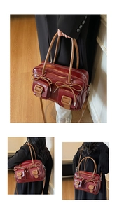 Detail of red vintage shoulder bag featuring twin front pockets and brown leather bows