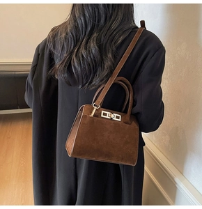 Detail of vintage brown suede crossbody bag featuring a rectangular metal twist lock