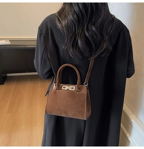 Detail of vintage dark brown suede handbag featuring a metal twist lock and smooth handle