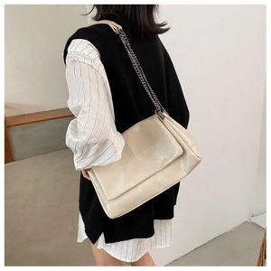 Close-up of beige quilted chain bag with polished leather texture and metallic strap