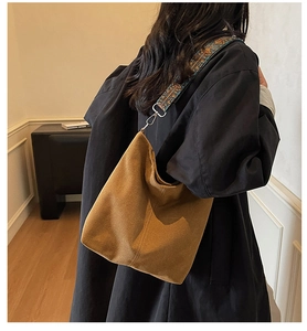 Detail of large tote bag with vintage patterned wide strap on a model's shoulder