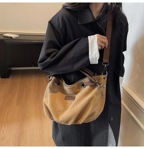 Detalle de bolso tote de lona caqui con asas de cuero marrón junto a un abrigo negro