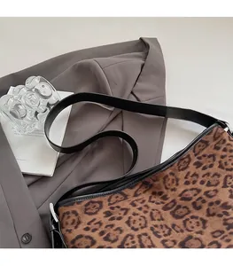 Dettaglio della comoda tracolla in pelle nera sulla borsa tote vintage in pelle scamosciata