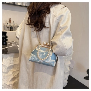 Détail de broderie florale sur sac en soie bleu clair avec poignée perle et chaîne dorée