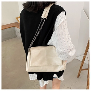 Model view showing the large cream chain shoulder bag worn across the back in a stylish setting