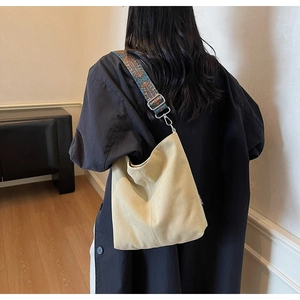 Detailed view of the wide ethnic embroidery strap on a beige canvas bucket bag