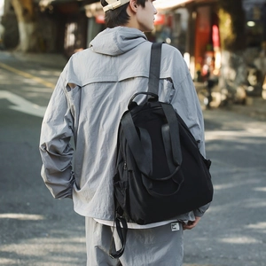 Minimalist black waterproof nylon backpack for women shown in an outdoor urban setting
