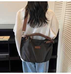 Detail of grey canvas tote bag with contrast brown leather handles and shoulder strap