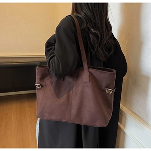 Detail of dark brown suede tote bag featuring side metal buckle and refined texture