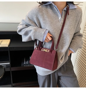 Macro detail of wine red suede bag featuring a gold metal twist lock and textured finish