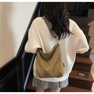 Detailed look at the canvas bucket bag with colorful embroidered wide strap on model