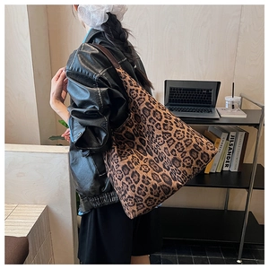 Detail view of large leopard print tote bag with brown shoulder strap in a cafe setting