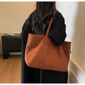 Detail of large orange-brown suede tote bag with adjustable metal side buckles