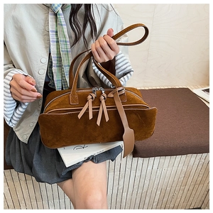 Detailed macro view of the brown suede handbag showing smooth texture and tassels