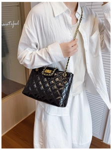 Detail of classic black quilted tote bag with gold chain strap and metal lock closure