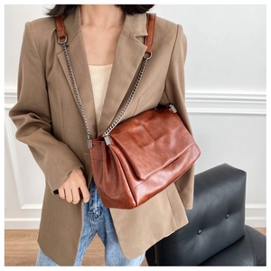 Detailed macro view of vintage brown leather texture and metal chain on shoulder bag