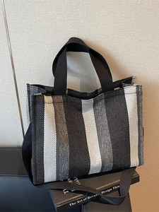 Vertical black and white striped canvas tote bag with dual handles and long shoulder strap