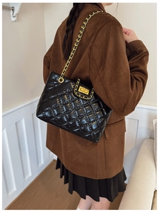 Close-up of quilted black leather tote with gold chain strap and turn-lock detail