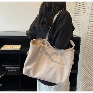 Detail view of large beige suede tote bag with adjustable side straps on female model
