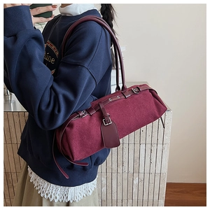 Detailed view of burgundy baguette bag with brown leather strap on model's shoulder