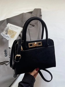 Vintage black suede crossbody bag with gold buckle on a stylish gray blazer