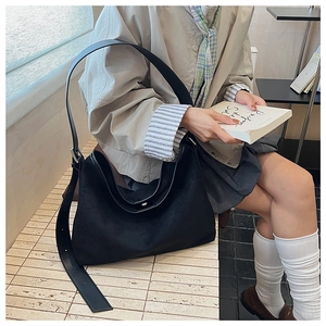 Dettaglio borsa hobo minimalista in pelle nera opaca con ampia tracolla regolabile e fibbia