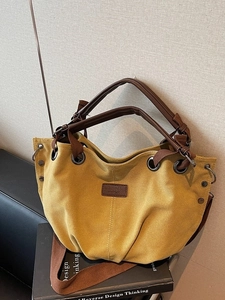 Vintage mustard yellow canvas tote bag with brown leather handles and adjustable shoulder strap