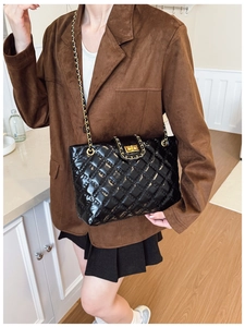 Quilted black leather tote bag with gold chain strap shown on a model's shoulder
