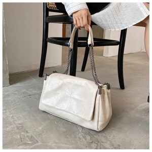 Detail of minimalist off-white PU leather tote with dark gray chain and metal accents